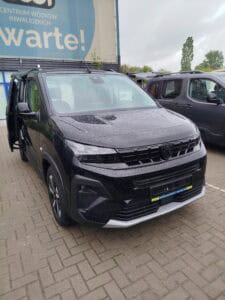 Widok od frontu na samochód marki Peugeot. Boczna para drzwi przesuwnych jest otwarta, odsłaniając wnętrze pojazdu