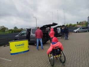 Ogólny widok placu na którym prezentowane są samochody dostosowane do potrzeb osób na wózkach, grupy osób oglądają pojazdy