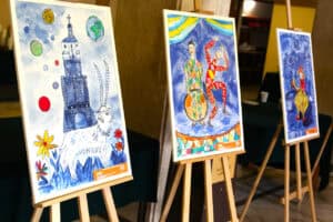 Wystawa prac artystycznych podopiecznych Stowarzyszenia Camino. Trzy obrazy wyeksponowano na drewnianych sztalugach