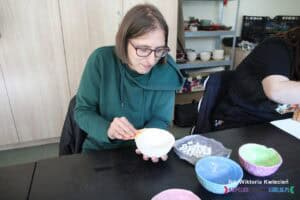 Uczestniczka starannie szlifuje ręcznie wykonaną ceramiczną miseczkę