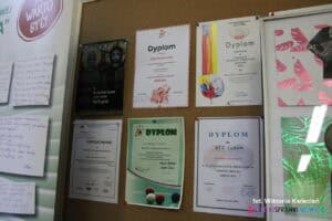 Tablica korkowa z wyeksponowanymi dyplomami dokumentującymi uczestnictwo w różnych formach aktywności społecznej i sportowej
