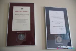 Na ścianie wiszą dwa wyróżnienia z okazji 15-lecia działalności WTZ: Dyplom Uznania od Wojewody Lubelskiego Lecha Sprawki oraz Medal Prezydenta Miasta Lublin dr Krzysztofa Żuka