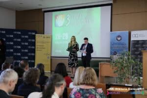 Uroczysta inauguracja III Lubelskich Dni Integracji. Prowadzący konferencję mgr Iwona Joć oraz mgr Paweł Robak na tle ekranu multimedialnego z identyfikacją wizualną wydarzenia; widok z widowni