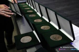 Starannie ułożony rząd pamiątkowych medali 35-lecia Nieprzetartego Szlaku (1990–2025), każdy w osobnym, otwartym etui z miękkim, zielonym aksamitem, który podkreśla rangę wyróżnienia