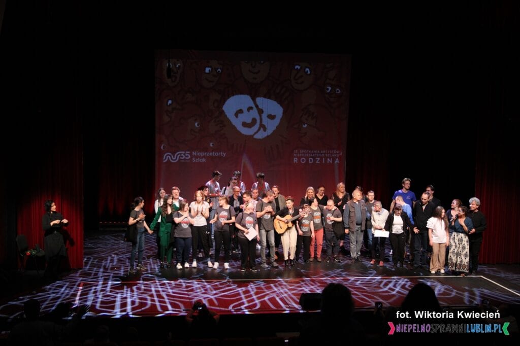 Wielki Finał 35. Jubileuszowych Spotkań Artystów Nieprzetartego Szlaku. Na scenie duża grupa osób, w tle plansza z grafiką masek teatralnych, napisem rodzina i logotypem Fundacji