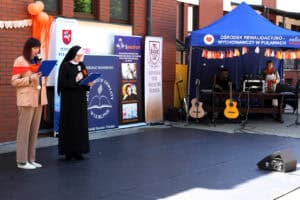 Na scenie prowadzące uroczystość: Angelika Tomasik i s. Kamila Benedyktynka Misjonarka. W prawej części kadru punkt techniczny z logo Ośrodka Rewalidacyjno – Wychowawczego w Puławach