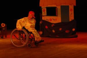 Spotkania Artystów Nieprzetartego Szlaku „Bajkowy Świat”, 2009. Aktorka na wózku inwalidzkim, w tle scenografia domku zdobionego malowanymi kwiatami