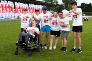 Uczniowie ze SOSW nr 1 wraz ze swoim trenerem, Jackiem Słupczyńskim, pozują do pamiątkowej fotografii na murawie stadionu, pokazując uniesione w górę kciuki. Wszyscy mają na sobie koszulki z napisem: 32. Bieg Solidarności i numery startowe