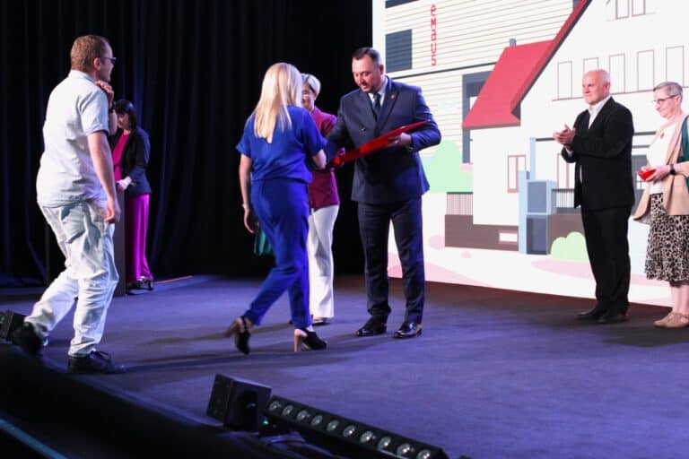 W centralnym punkcie kadru Wicemarszałek Województwa Lubelskiego Marek Wojciechowski wręczający nagrody i wyróżnienia gościom wchodzącym na scenę