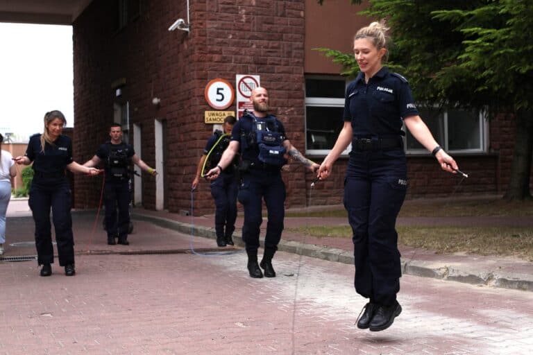 W kadrze grupa policyjna. Trzech mężczyzn i dwie kobiety. Wszyscy skaczą na skakankach
