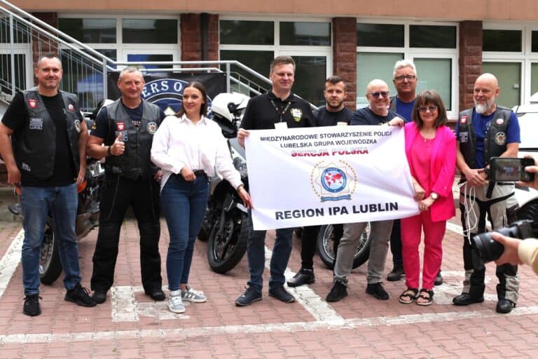 Pamiątkowa fotografia grupowa. Kilka osób trzyma transparent z napisem: Międzynarodowe Stowarzyszenie Policji. Lubelska Grupa Wojewódzka. Sekcja Polska. Region IPA Lublin