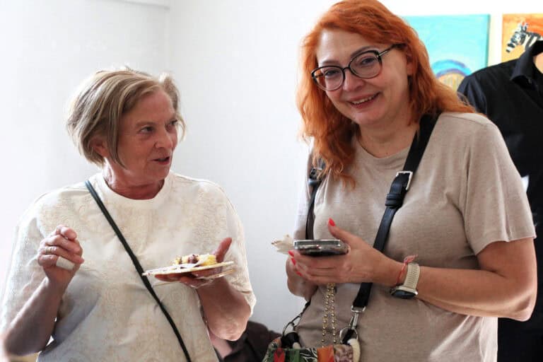 Dwie kobiety podczas rozmowy. Jedna z kobiet patrzy w obiektyw, uśmiecha się