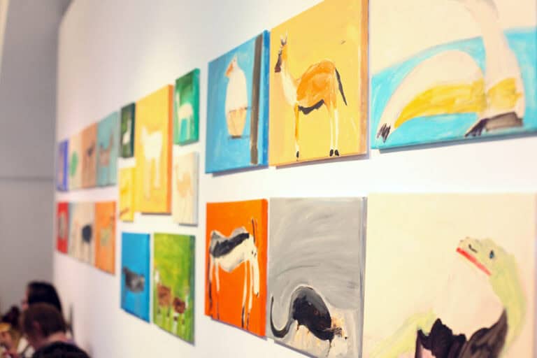 Rzut (w perspektywie zbieżnej) na ścianę z wyeksponowanymi obrazami, przedstawiającymi kolorowe zwierzęta
