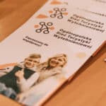 Zbliżenie na ulotki z logo Ogólnopolskiej Sieci Turystyki Wytchnieniowej i zaproszeniem do współpracy; ulotkę ilustruje zdjęcie chłopca siedzącego na wózku inwalidzkim przy którym stoi kobieta