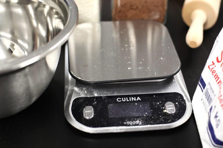 Culina – mówiąca waga kuchenna, przeznaczona dla osób z dysfunkcjami wzroku. Waga jest oprószona mąką. Po lewej fragment miski ze stali nierdzewnej, po prawej fragment drewnianego wałka do ciasta i torebka z mąką ziemniaczaną