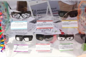 Gablota ze specjalistycznymi okularami symulującymi choroby oczu. Ułożone są w dwóch rzędach. Przed każdą parą tabliczka informująca o chorobie oczu. Kolejno: retinopatia cukrzycowa, zaćma, jaskra, niedowidzenie połowiczne, zwyrodnienie barwnikowe siatkówki i zwyrodnienie plamki żółtej