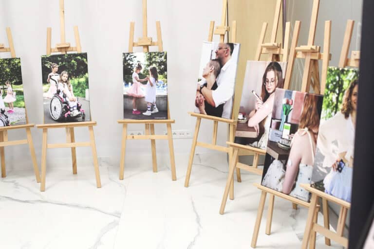 Ekspozycja siedmiu kolorowych fotografii na sztalugach, które ustawiono w kształt półkola. Stoją na jasnej podłodze, w tle jasna ściana