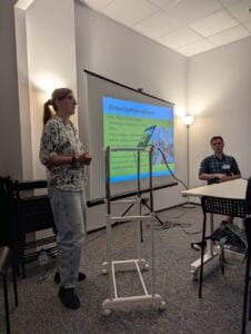 Prowadząca szkolenie – Justyna Mańkowska-Kaczmarek, mówi do słuchaczy. Po jej prawej stronie siedzi tłumacz Polskiego Języka Migowego – Łukasz Grzesiuk.