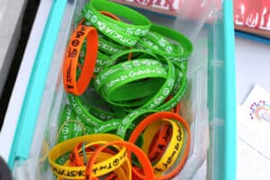 W przezroczystym plastikowym pudełku z turkusowym rantem leżą gumowe bransoletki na rękę z napisem: Jestem za Godnością i Tour de Konstytucja. Bransoletki są w trzech kolorach: żółtym, pomarańczowym i zielonym. Napisy białe lub czarne