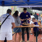 Rodzice z dziećmi w trakcie posiłku przy stoliku, pod parasolem