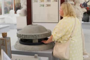 Miniatura Pomnika – Mauzoleum na terenie byłego niemieckiego obozu koncentracyjnego KL Lublin. Przed miniaturą stoi kobieta, której dłoń spoczywa na tym eksponacie. W tle wnętrze sali wystawienniczej