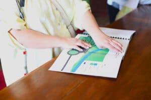 Kobiece dłonie dotykają kart mapy – przewodnika, leżącej na drewnianym blacie