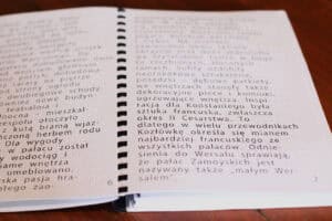 Zbliżenie na karty przewodnika z opisem historycznym. Fokus na dużej czcionce i tłumaczeniu na alfabet Braille’a