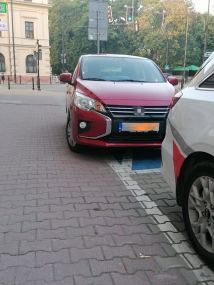 Miejsce parkingowe dla osób z niepełnosprawnościami przy skrzyżowaniu ulic Chopina i Krakowskiego Przedmieścia zajęte przez krzywo zaparkowany pojazd osobowy, nie mieszczący się w wymalowanych liniach