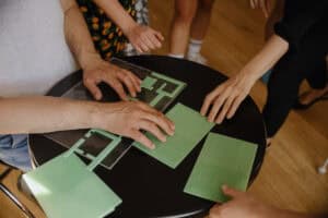 Ręce kilku osób oglądających, położone na czarnym stoliku, modele planów tyflograficznych