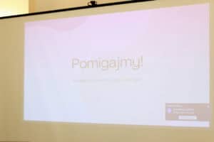 Pełnoekranowy slajd prezentacji, który wita uczestników szkolenia. Centralny napis w kolorze czarnym głosi: "Pomigajmy!", a poniżej znajduje się podtytuł: "Spotkanie o kulturze i języku Głuchych"