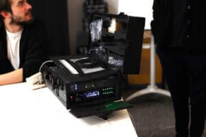 Szczegółowe zbliżenie na sprzęt elektroniczny (pętla indukcyjna) w otwartej walizce transportowej. Widoczny wyświetlacz cyfrowy i świecące zielone diody sygnalizują, że urządzenie jest włączone i aktywne podczas szkolenia