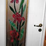 Białe wewnętrzne drzwi ozdobione kolorowym, szklanym witrażem z motywem kwiatowym