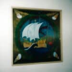 Kwadratowa, drewniana rama, wypełniona witrażowym obrazem z motywem morskim