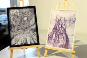 Dwie grafiki Jana Kaweckiego w czarnej i białej ramce stoją na sztalugach.