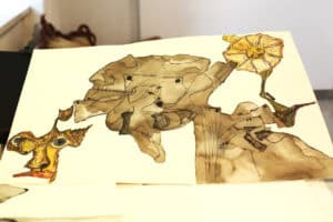 Gotowy rysunek leży na stole. Przedstawia złożoną, wielopostaciową formę wykonaną czarnym tuszem i wypełnioną charakterystycznym dla autora, gęstym żółto-brązowym kreskowaniem.