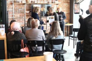 Edyta Filipczak odbiera certyfikat i wymienia uścisk dłoni z kobietą w granatowej bluzce. Obok stoi Marta Rak z ramką w rękach.