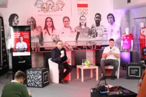 Ujęcie studyjne wydarzenia – po lewej Paweł Markiewicz zadaje pytanie, po prawej Michał Szyba słucha, między nimi stolik z piłką i medalem, w tle zdjęcia sportowców