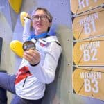 Agnieszka Kwolek stoi na tle ścianki wspinaczkowej z brązowym medalem Pucharu Świata w parawspinaczce podczas zawodów we francuskim Laval (25–26.10.2025) w kategorii B3; fot. stowarzyszenie Skocznia