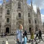 Mediolan, Włochy, 2025. Małgorzata Tokarska stoi na placu przed Katedrą Narodzin św. Marii, wspiera się na kuli; wokół przechodzą turyści, na bruku gromadzą się gołębie