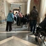 Rzym, Watykan, 2025. Turyści zwiedzają muzealne wnętrze. Wśród nich są osoby z niepełnosprawnością ruchową: o kulach i na wózkach