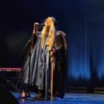 Występ wokalny Sebastiana podczas 28. Spotkań z Piosenką Nieprzetartego Szlaku „Fantasy” (27–29 października 2025). Mężczyzna w stroju maga ma na sobie długą czarną pelerynę z kapturem i perukę z długimi blond włosami. Prawą ręką trzyma mikrofon na statywie, w lewej ręce kostur; fot. Anna Bieganowska-Skóra