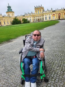 Paweł G. Iwaniuk pozuje na tle zabudowy Pałacu w Wilanowie.