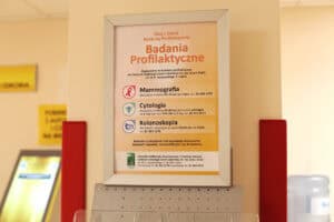Plakat w srebrnej ramie informuje o bezpłatnych badaniach profilaktycznych w Centrum Onkologii Ziemi Lubelskiej: mammografii, cytologii oraz kolonoskopii wraz z informacjami o grupach wiekowych i numerami telefonów do rejestracji