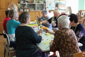 Seniorki siedzą przy stole podczas zajęć manualnych