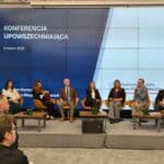 Ośmiu uczestników panelu dyskusyjnego siedzi na tle ekranu multimedialnego z widocznym u góry napisem "Konferencja upowszechniająca, 9 marca 2026"