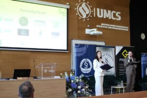 Kobieta i mężczyzna prowadzący konferencję na scenie Wydziału Prawa i Administracji UMCS. W tle ekran z logotypami partnerów forum.