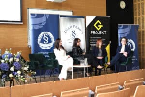 Panel dyskusyjny z udziałem czterech kobiet siedzących w fotelach na scenie. W tle banery organizacji prawniczych.