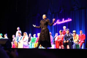 Musical pt. "Witajcie w naszej bajce" w wykonaniu Zespołu Inscenizacji Teatralnych "Uśmiech" z Kielc. Na scenie stoi aktorka w czarnej, gotyckiej sukni z gorsetem, z szeroko rozpostartymi ramionami. Za nią siedzi duża grupa artystów w kolorowych strojach. W tle, na fioletowej kurtynie, świeci fioletowy neonowy napis „Akademia”.