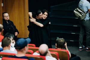 Uśmiechnięta uczestniczka obejmuje tłumaczkę Polskiego Języka Migowego (PJM) przed wejściem na scenę; kobiety stoją w serdecznym uścisku; fot. Konrad Drobek