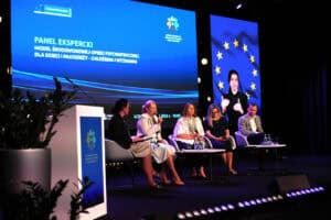 Na scenie pięciu uczestników panelu eksperckiego. W tle niebieski ekran z napisem: „Panel ekspercki. Model środowiskowej opieki psychiatrycznej dla dzieci i młodzieży – założenia i wyzwania”. Po prawej stronie ekran z tłumaczką języka migowego.